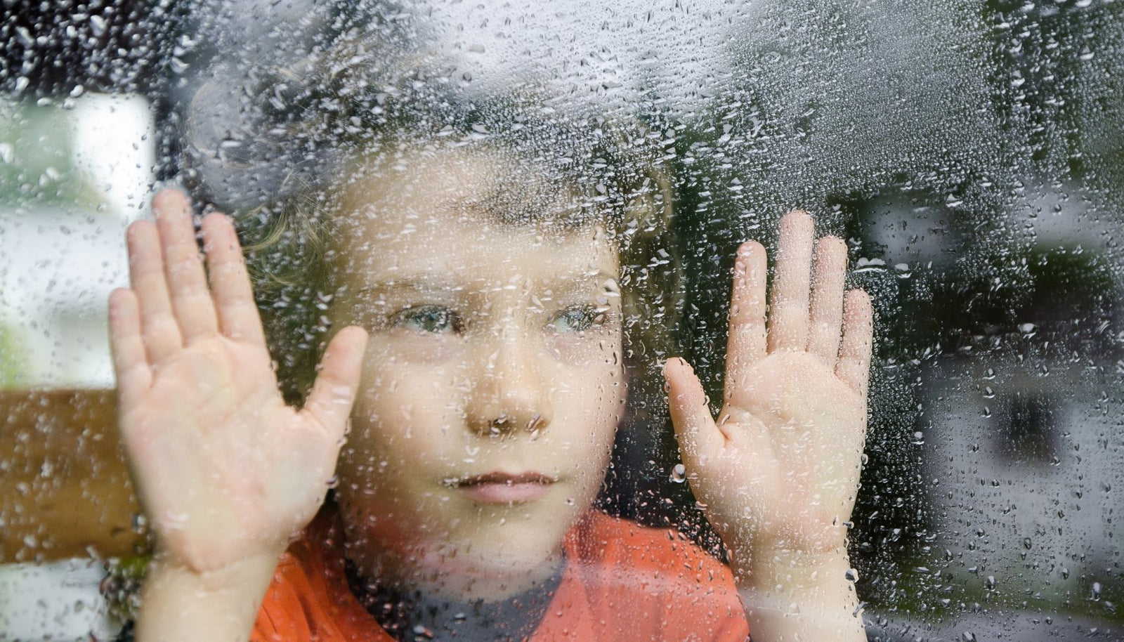 Image of a child looking out the window at the rain.